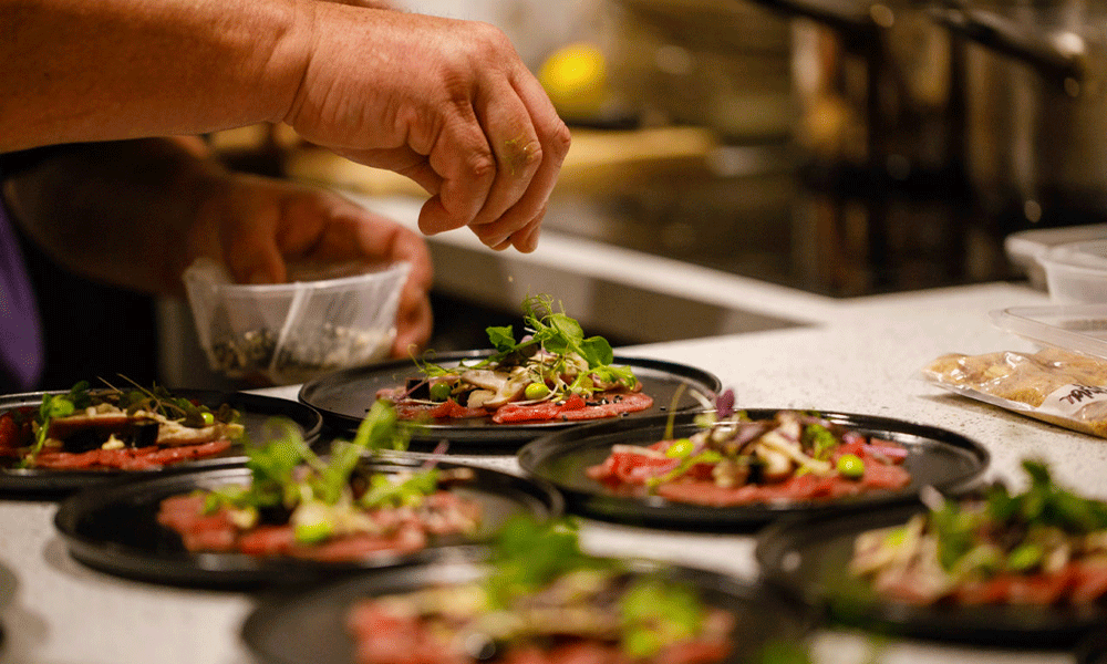 Chef's hand garnishing beautifully plated food before serving
